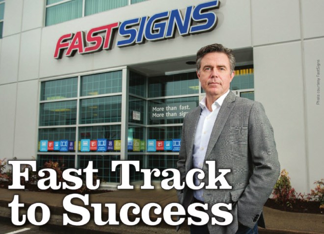Paul LeBlanc poses outside of a FASTSIGNS with text saying "Fast Track to Success"